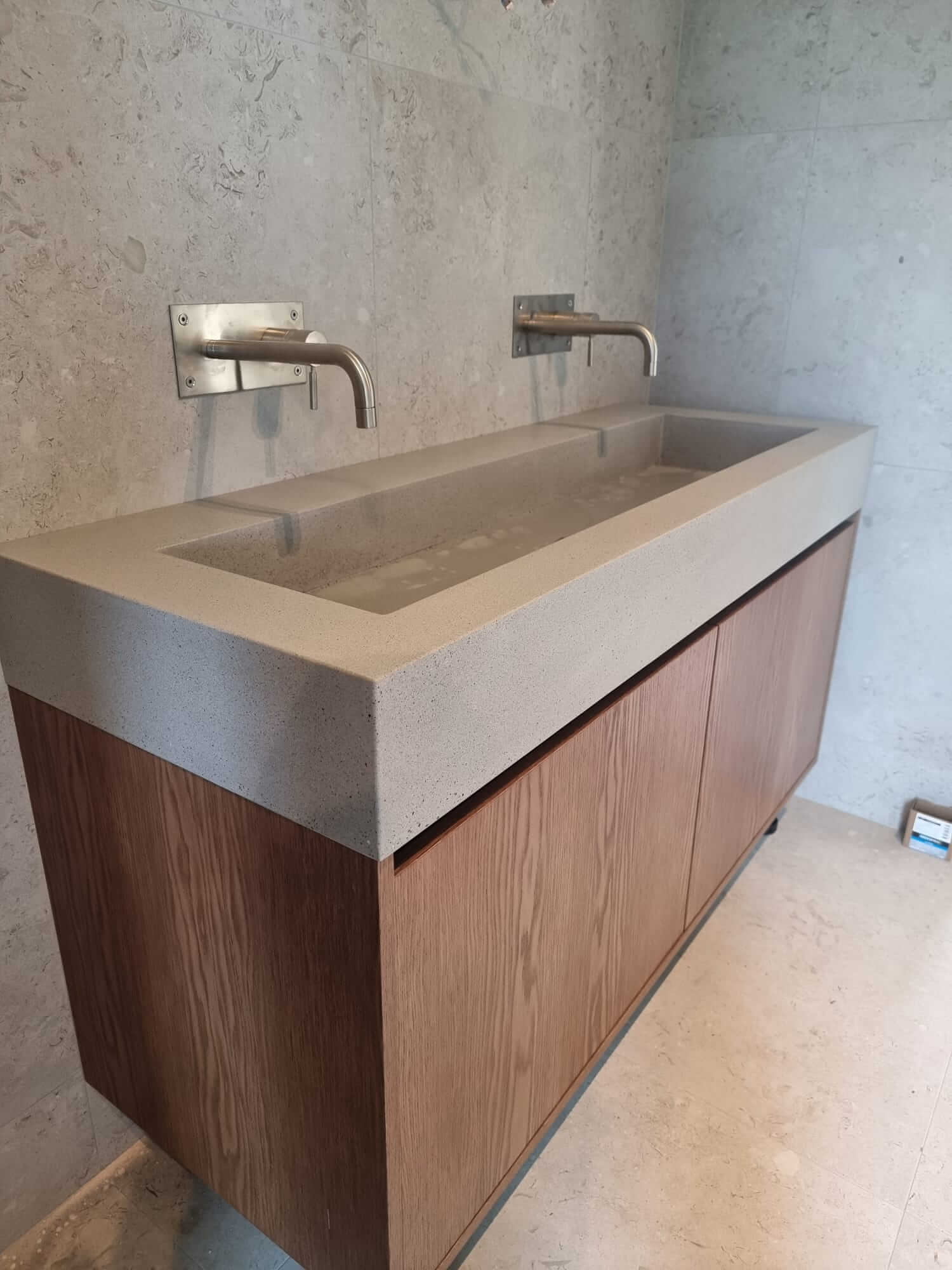 Concrete bathroom countertop with double sinks and wooden cabinets
